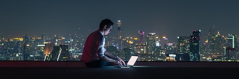 Man working on computer on city rooftop