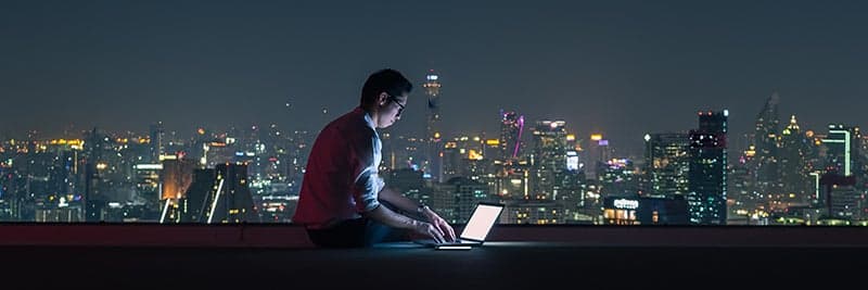 Man working on computer on city rooftop